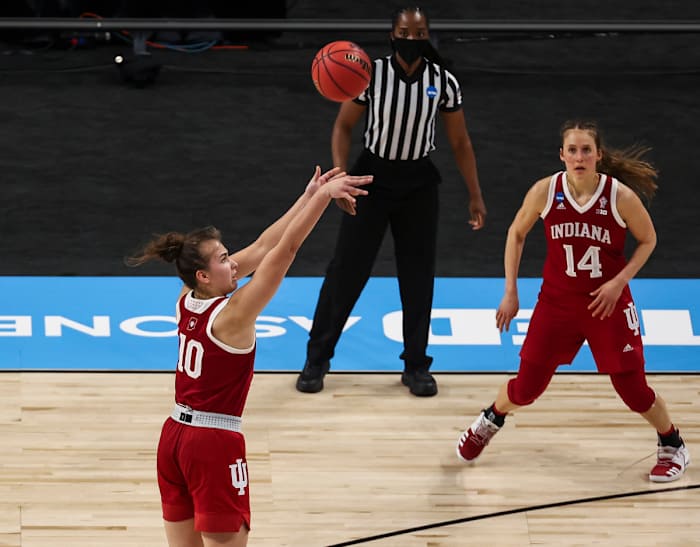 Aleksa Gulbe shoots the ball while Ali Patberg watches in the distance.