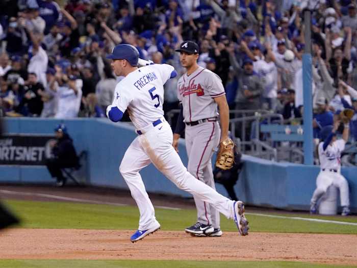 Los Angeles Dodgers’ Freddie Freeman, left, rounds first after hitting a solo home run as Atlanta Braves first baseman Matt Olson watches during the first inning of a baseball game Monday, April 18, 2022, in Los Angeles.