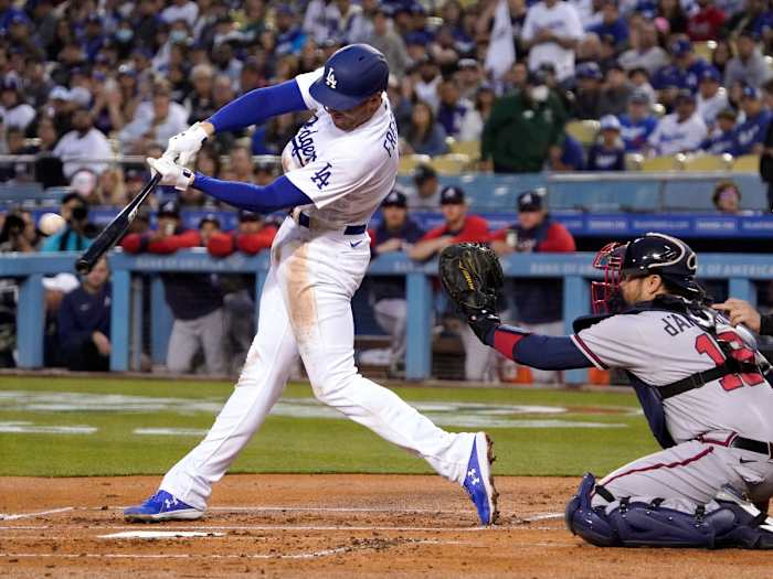 Los Angeles Dodgers’ Freddie Freeman, left, hits a solo home run as Atlanta Braves catcher Travis d’Arnaud watches during the first inning of a baseball game Monday, April 18, 2022, in Los Angeles.
