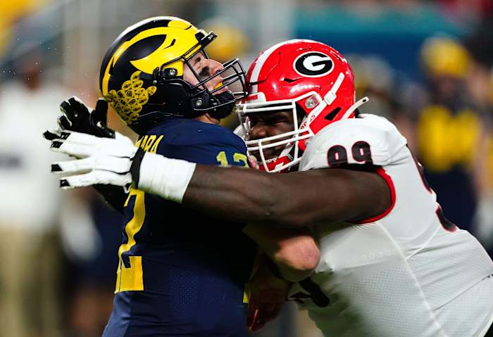 Michigan quarterback Cade McNamara (12) is hit by Georgia defensive lineman Jordan Davis (99) during the CFP national semifinal game. Mandatory Credit: John David Mercer-USA TODAY