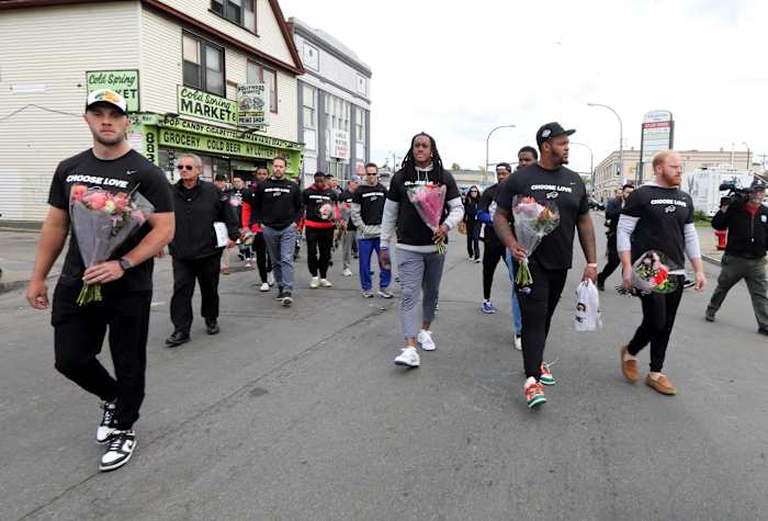 Members of the Buffalo Bills walk to the site of the last Saturday's mass shooting at the Tops supermarket in Buffalo. After visiting the site, the team helped distribute food to members of the community.