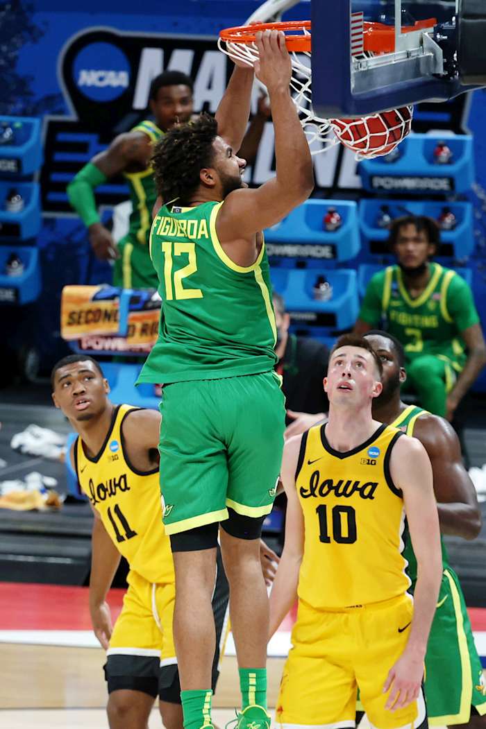 LJ Figueroa (12) throws down a dunk in the NCAA Tournament while Iowa's Joe Wieskamp (10) and Tony Perkins (11) look on.