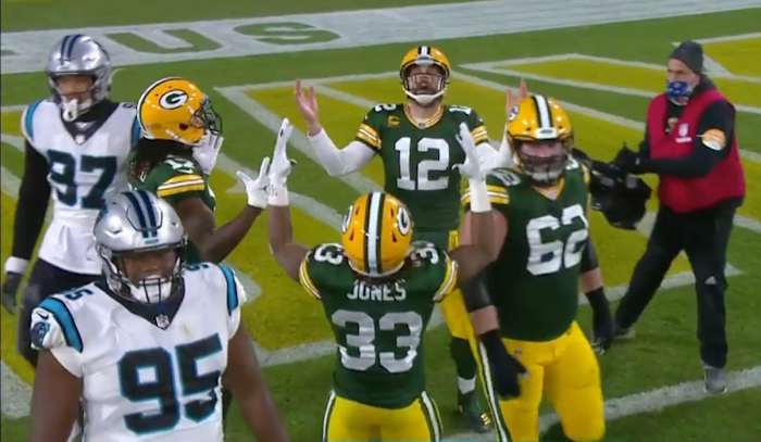 Aaron Rodgers, Davante Adams and Aaron Jones look up, hands raised, as they celebrate a touchdown against the Panthers during a 2020 game