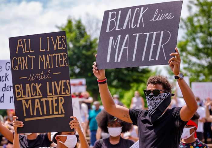 Norman native and Atlanta Hawk basketball player Trae Young, right, gathers with others protesters as they carry signs during a protest at Andrews Park on Monday, June 1, 2020.