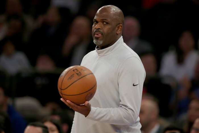Nate McMillan holds a basketball on the sidelines.