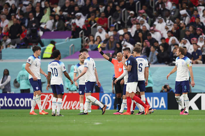 Referee Wilton Sampaio pictured showing a yellow card to Harry Maguire (left) during the 2022 World Cup quarter-final between England and France