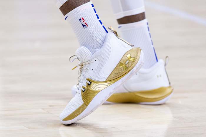 View of white and gold Under Armour shoes.