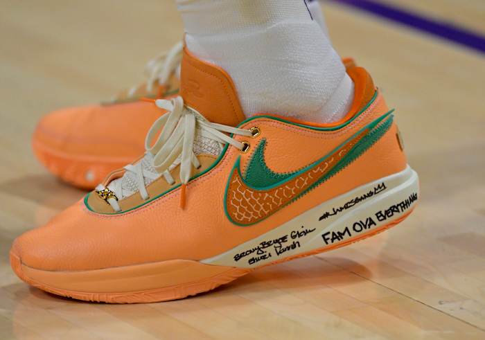 View of orange and green Nike LeBron shoe.