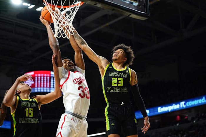 Cincinnati Bearcats forward Ody Oguama (33) rises to the basket as South Florida Bulls guard Caleb Murphy (23) and South Florida Bulls forward Corey Walker Jr. (15) defend in the first half of a men's NCAA basketball game, Saturday, Feb. 26, 2022, at Fifth Third Arena in Cincinnati. South Florida Bulls At Cincinnati Bearcats Basketball 103