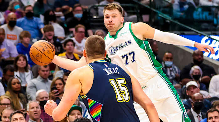 Luke Dončić tries to fire a pass past Nikola Jokić.