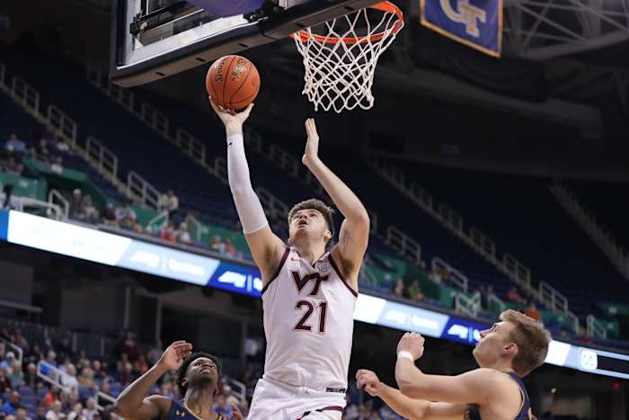 Mar 7, 2023; Greensboro, NC, USA; Virginia Tech Hokies forward Grant Basile (21) shoots as Notre Dame Fighting Irish guard Marcus Hammond (10) and guard Dane Goodwin (23) defend in the second half at Greensboro Coliseum. Mandatory Credit: Bob Donnan-USA TODAY Sports