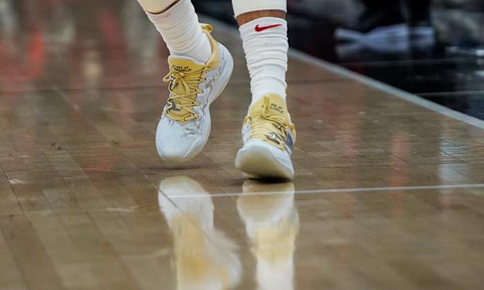 View of white and gold New Balance shoes.