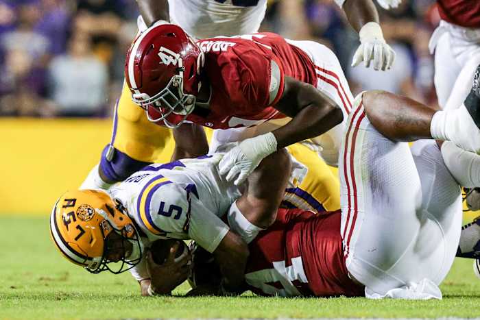 Nov 5, 2022; Baton Rouge, Louisiana, USA; LSU Tigers quarterback Jayden Daniels (5) is tackled by Alabama Crimson Tide defensive lineman DJ Dale (94) and linebacker Chris Braswell (41) during the second half at Tiger Stadium.