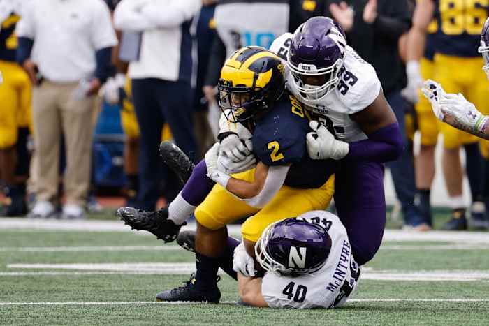 Michigan Wolverines running back Blake Corum (2) is tackled by Northwestern Wildcats linebacker Peter McIntyre (40) and defensive lineman Adetomiwa Adebawore (99) in the first half at Michigan Stadium.