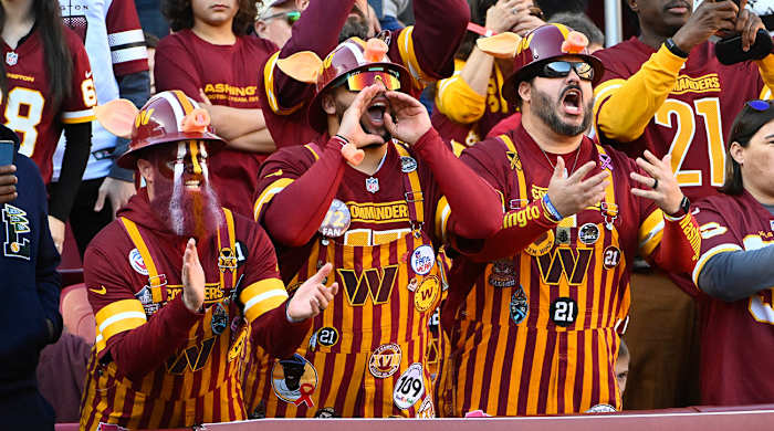 Commanders fans in overalls cheer from the stands.
