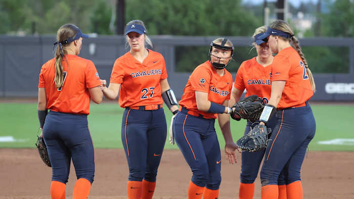 The Virginia softball team meets in the pitching circle during the game against Louisville at Palmer Park.