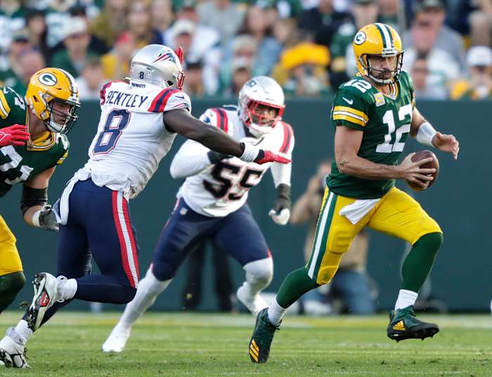 Green Bay Packers quarterback Aaron Rodgers runs the ball against New England Patriots defenders.