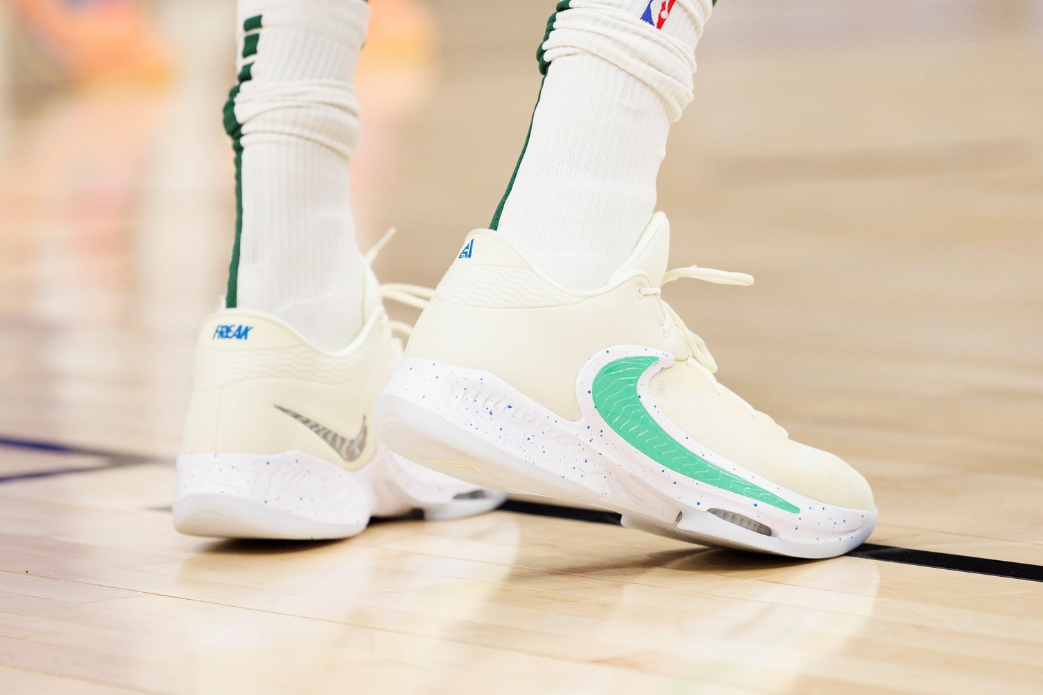 View of Giannis Antetokounmpo's cream and green Nike shoes.