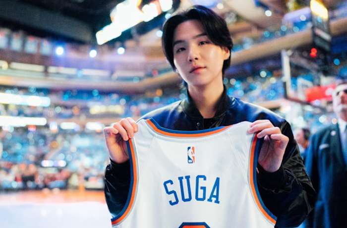 Suga holds up a Knicks jersey before a game.