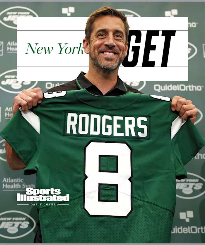 Aaron Rodgers holding up his new Jets jersey at a press conference, with text that says New York GET