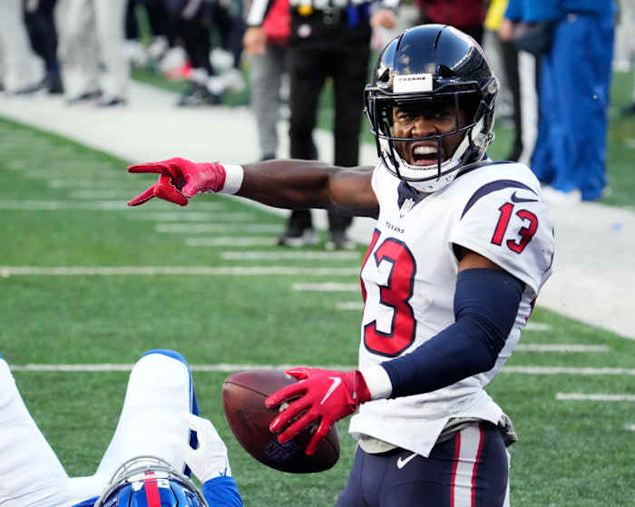 Brandin Cooks holds the ball with one hand and makes a hand signal with the other, yelling in celebration