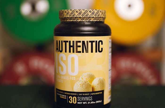 Jacked Factory Authentic ISO in a black container with a yellow label, blurred weight plates in the background