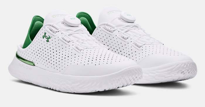 Side view of white and green Under Armour shoes.