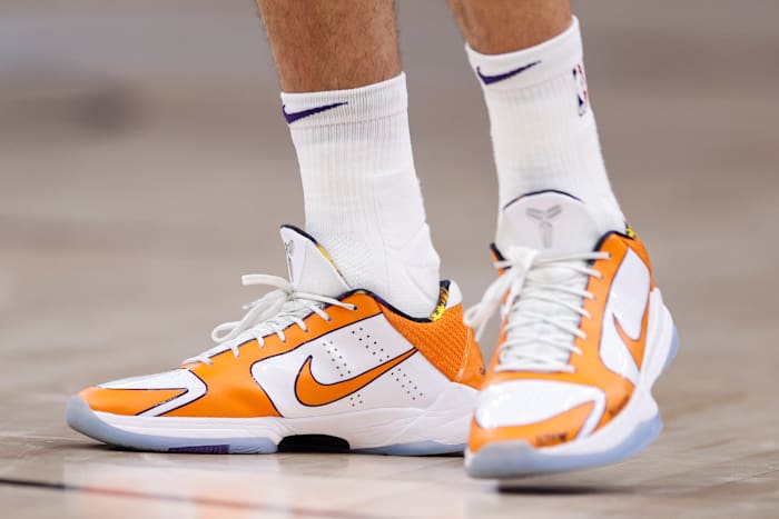 View of Devin Booker's orange and white Nike shoes.