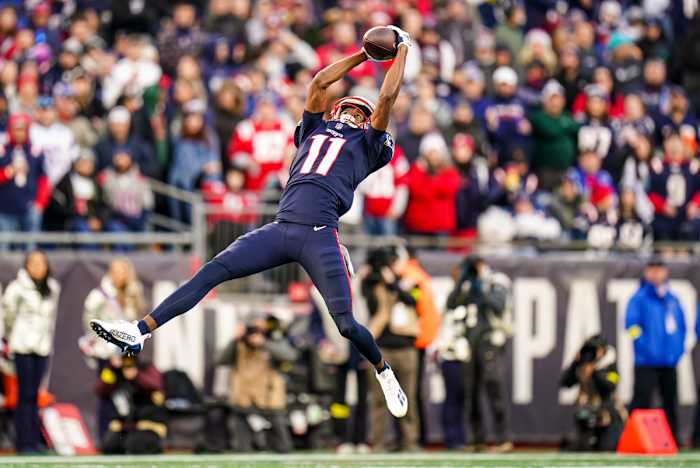 Tyquan Thornton jumps in the air with both hands reaching up to make a catch