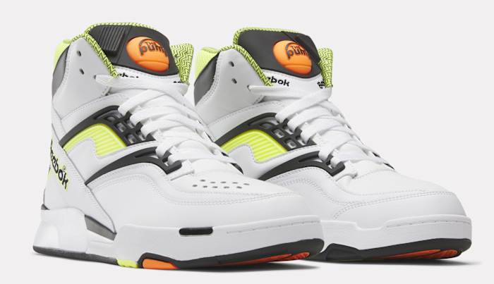 Side view of white, black, and yellow Reebok shoes.