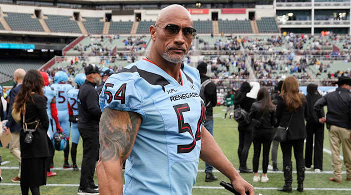 Dwayne Johnson wearing an XFL uniform in a stadium
