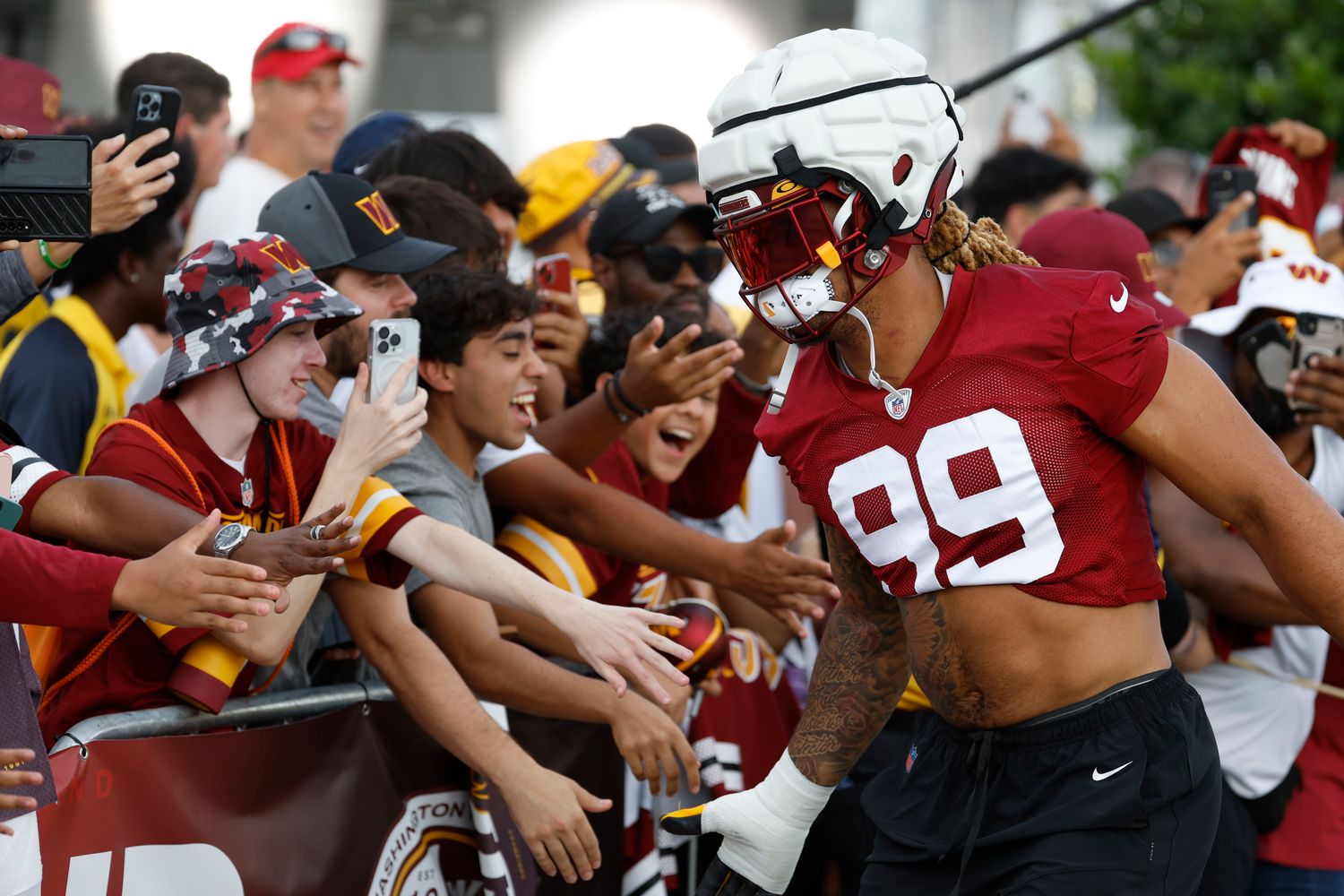 Washington Commanders defensive end Chase Young (99) shakes hands with fans while walking to the fields prior to day two of Commanders training camp at OrthoVirginia Training Center.