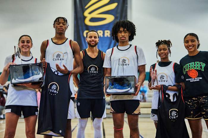 Stephen Curry poses for a picture with kids at his basketball camp.