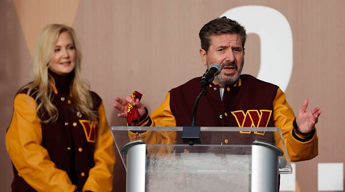 Commanders co-owner Dan Snyder speaks as co-owner Tanya Snyder (L) listens during a press conference.