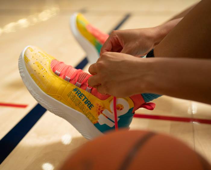 Azzi Fudd laces up a pair of #RetireInequality shoes.