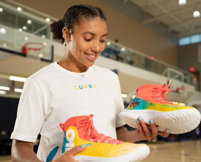 Azzi Fudd holds a pair of #RetireInequality custom shoes.