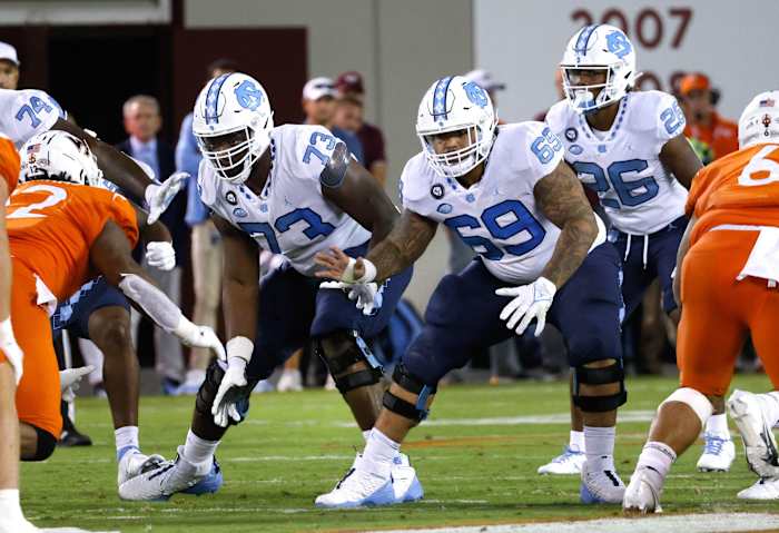 Sep 3, 2021; Blacksburg, Virginia, USA; North Carolina Tar Heels offensive linemen Marcus McKethan (73) and Quiron Johnson (69) and running back D.J. Jones (26) react to the snap during the second half against the Virginia Tech Hokies at Lane Stadium.