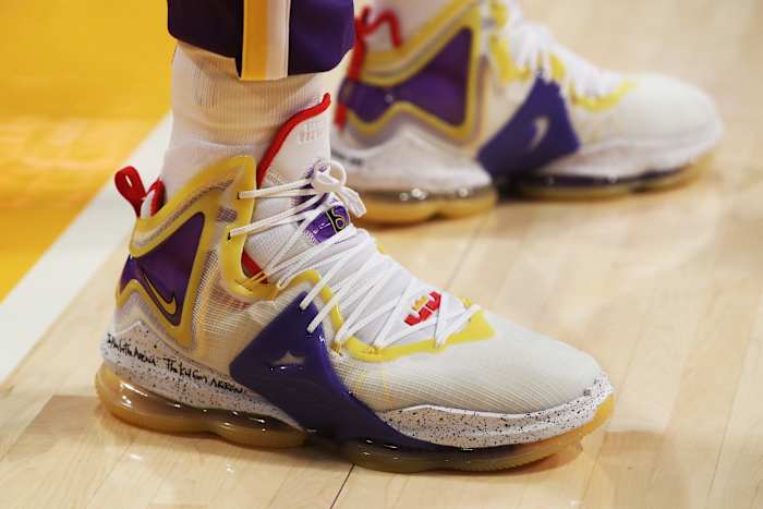 View of white, purple, and gold Nike LeBron 19 shoes.