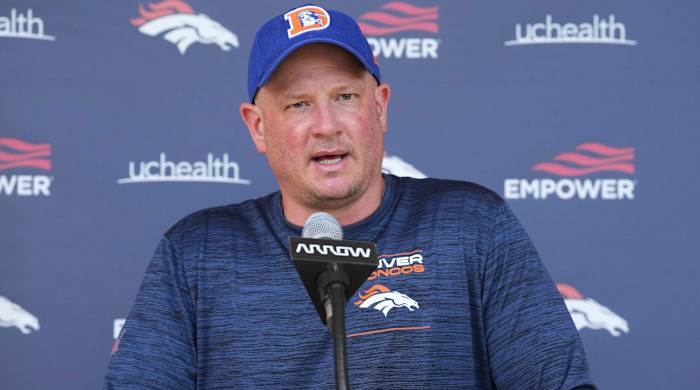 The Broncos coach speaking at a podium.