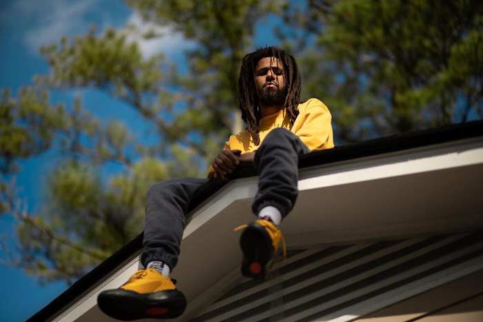 J. Cole sitting on a roof.