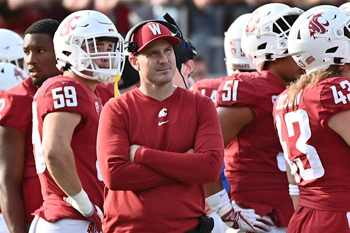 Washington State head coach Jake Dickert standing on the sidelines with his team.