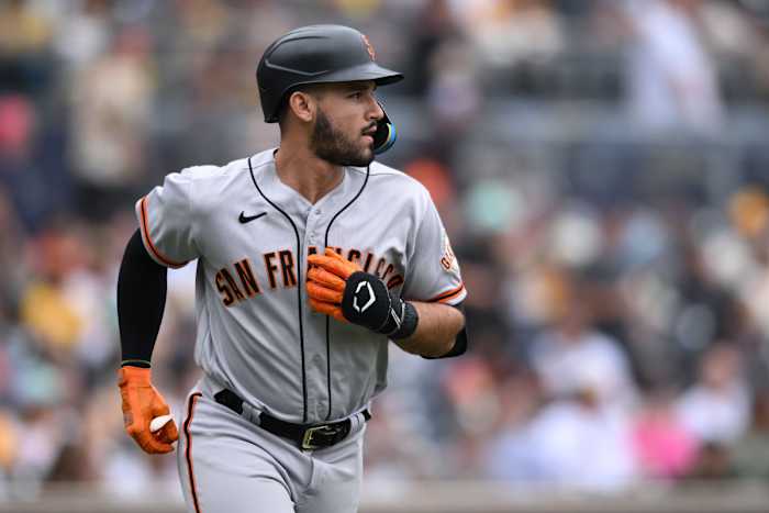 SF Giants infielder runs down the first base line after hitting the ball against the Padres.