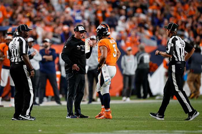 Denver Broncos head coach Nathaniel Hackett talks with quarterback Russell Wilson (3) as side judge Anthony Jeffries (36) and down judge Kent Payne (79) look on in the fourth quarter against the Indianapolis Colts at Empower Field at Mile High.