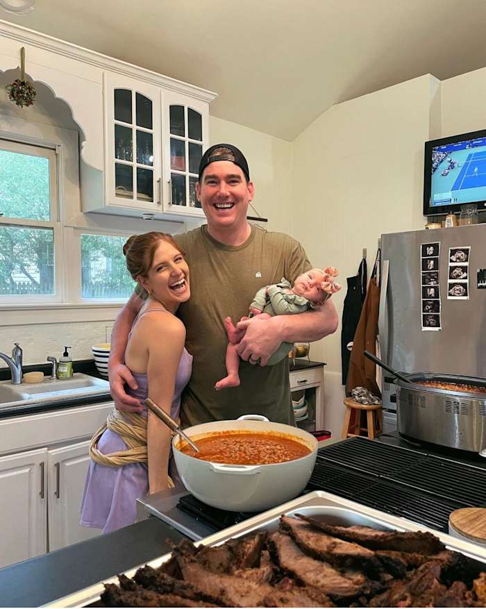 Tom and Rachael Sullivan pose in their kitchen holding their newborn baby