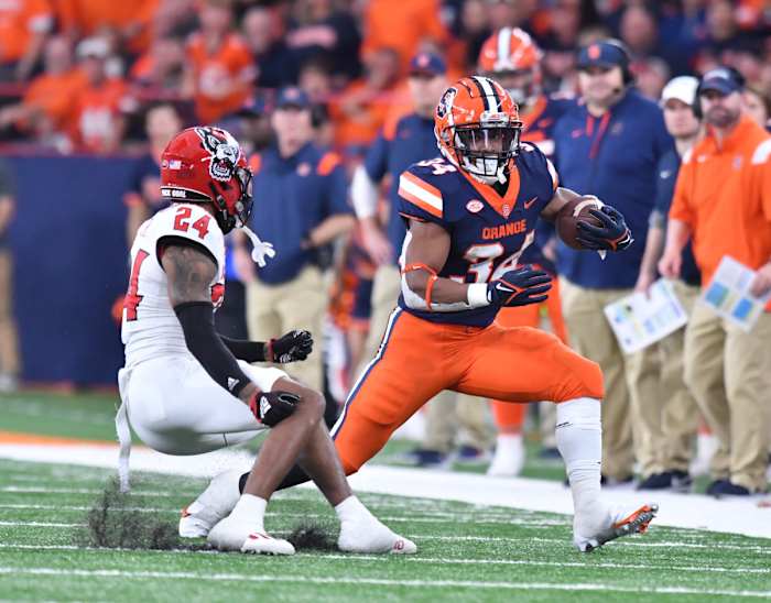 Syracuse RB #34 Sean Tucker makes a move against the NC State defender (#24 Derrek Pitts Jr.)