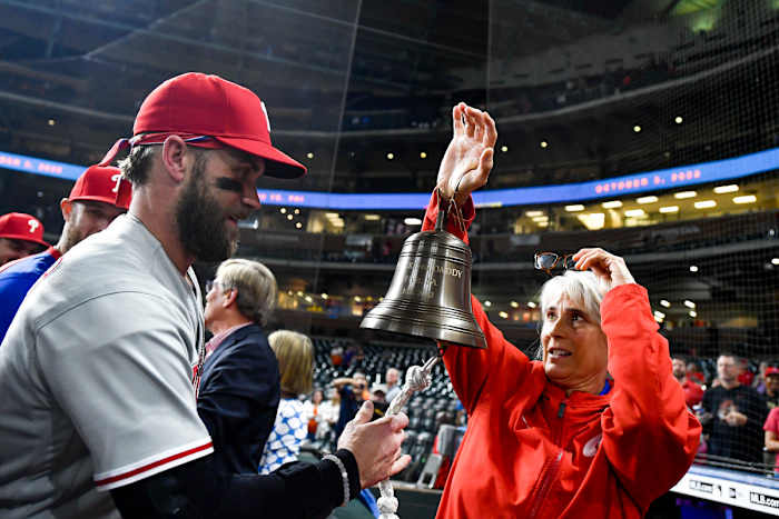 Bryce Harper rings the Phillies’ liberty bell, held by Sheree McMullen, after beating the Padres in NLCS Game 5 to clinch the NL pennant and a trip to the World Series.