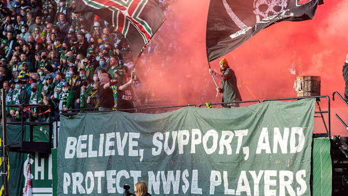 Portland Thorns fans hold up a banner that says, “Believe, support, and protect NWSL players.”