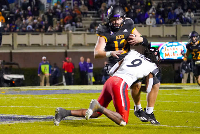 Nov 26, 2021; Greenville, North Carolina, USA; East Carolina Pirates quarterback Holton Ahlers (12) is stopped on his run by Cincinnati Bearcats cornerback Arquon Bush (9) during the second half at Dowdy-Ficklen Stadium. Mandatory Credit: James Guillory-USA TODAY Sports