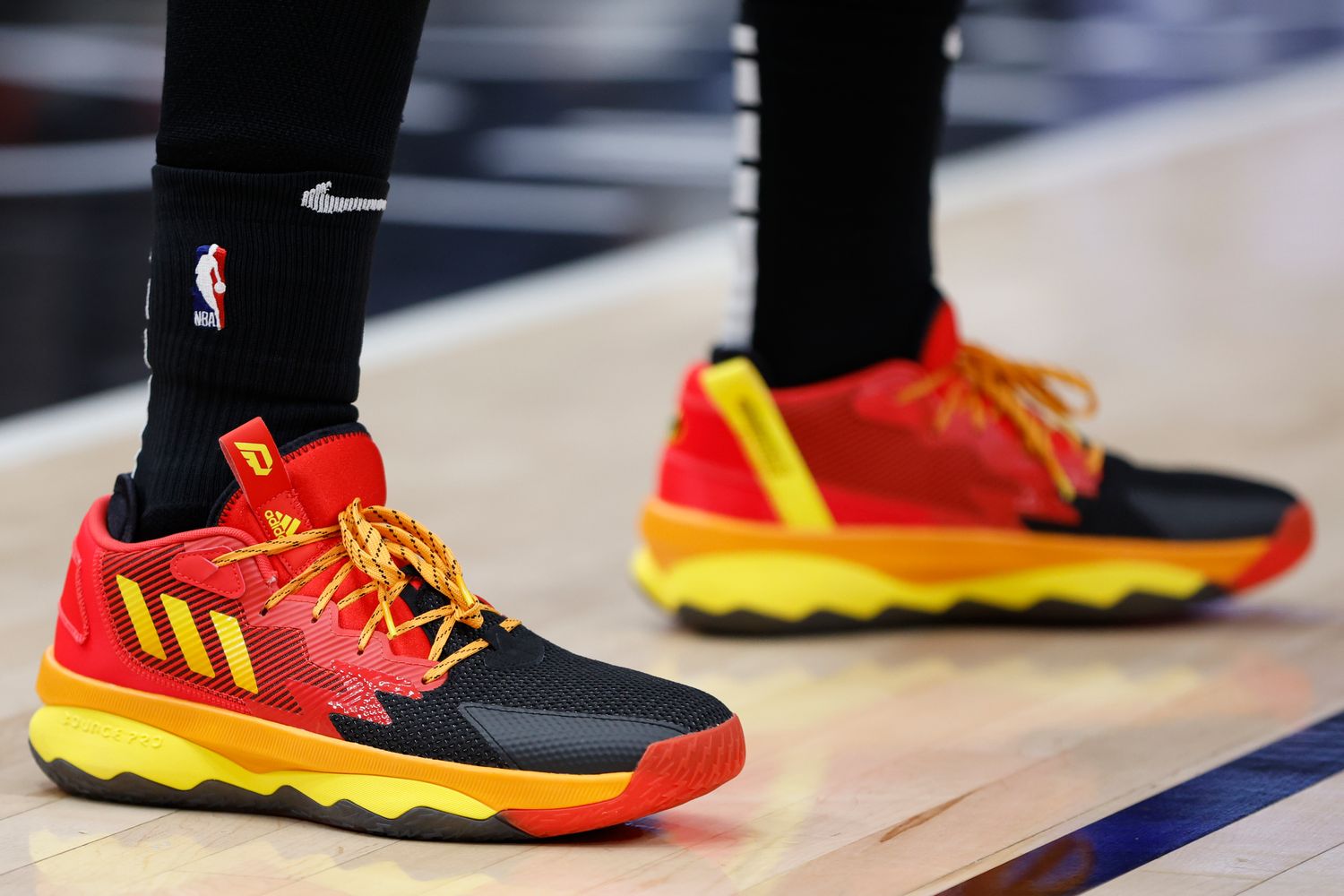 Red, black, and yellow Adidas Dame shoes.