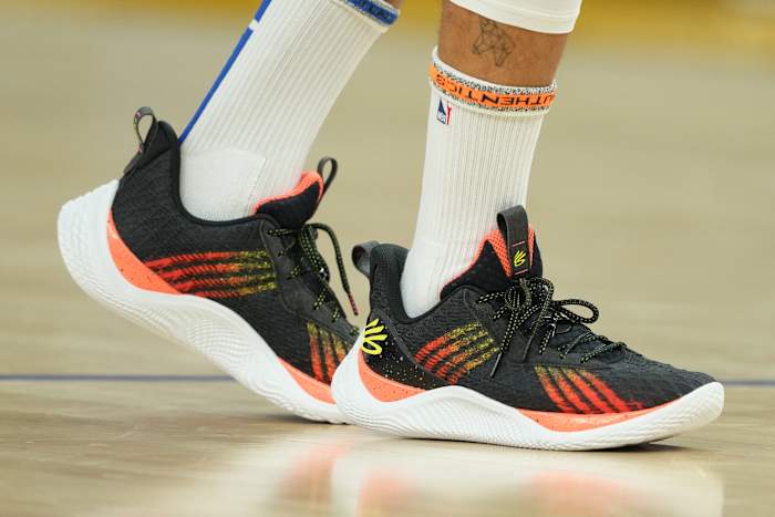 View of black, orange, and white Curry shoes.